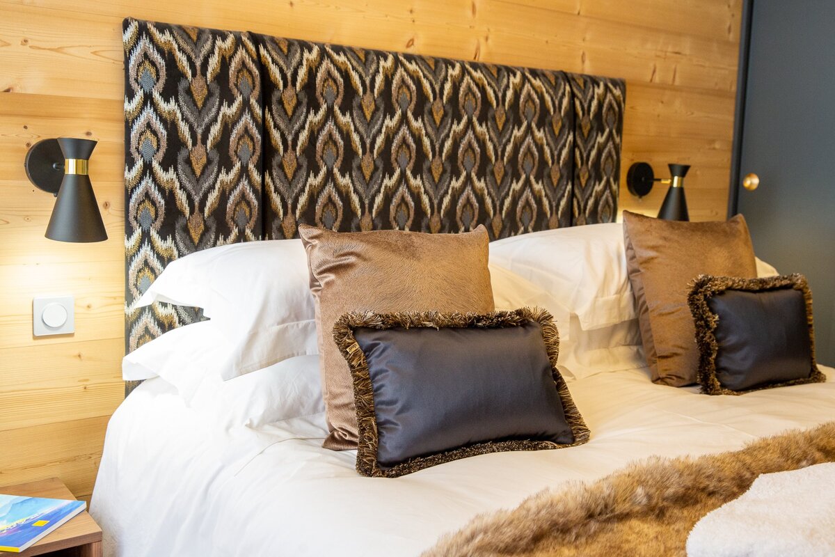 A bed with pillows and a book on a nightstand