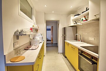 A kitchen with yellow cabinets and a stainless steel refrigerator