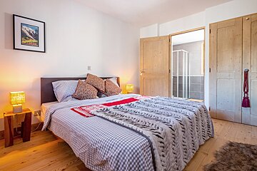 A bedroom with a bed and a picture of a mountain on the wall