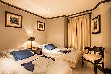 A bedroom with two beds and two pictures on the wall