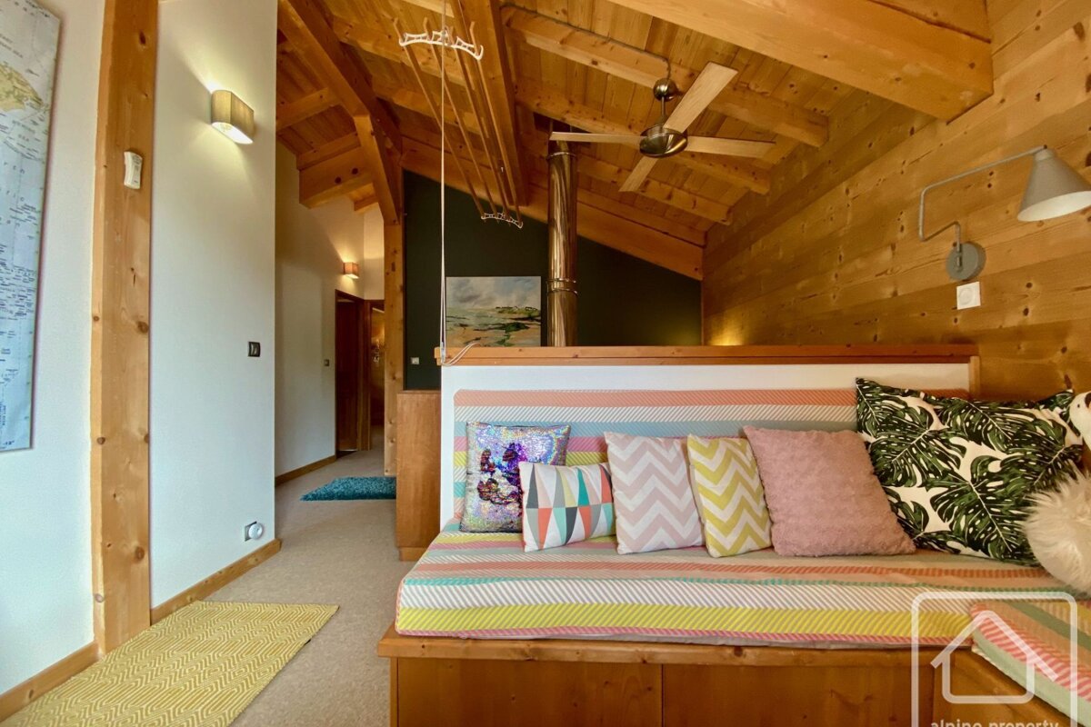 A wooden couch with colorful pillows sits in a hallway