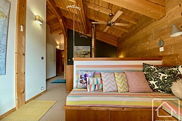 A wooden couch with colorful pillows sits in a hallway