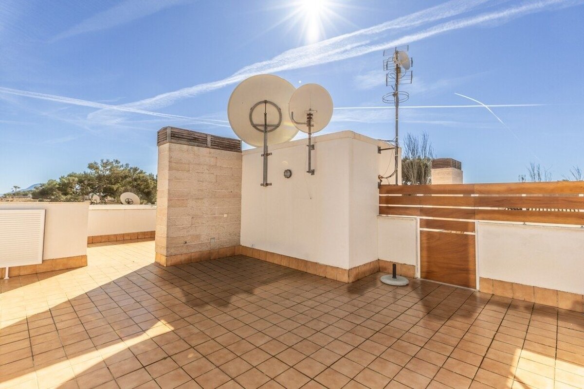 Sunny rooftop terrace with brown tiles, satellite dishes, and an antenna under a bright blue sky.