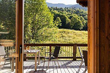 A deck with a table and chairs and a view of a forest