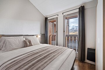 A bedroom with a large bed and a balcony
