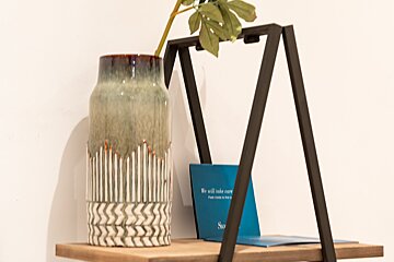 A vase sits on a shelf next to a sign that says we will take care