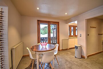 A kitchen with a table and chairs and a trash can