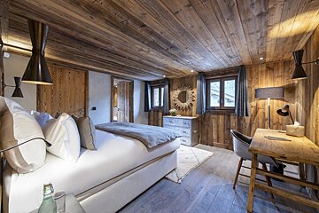 A bedroom with a large bed and a desk