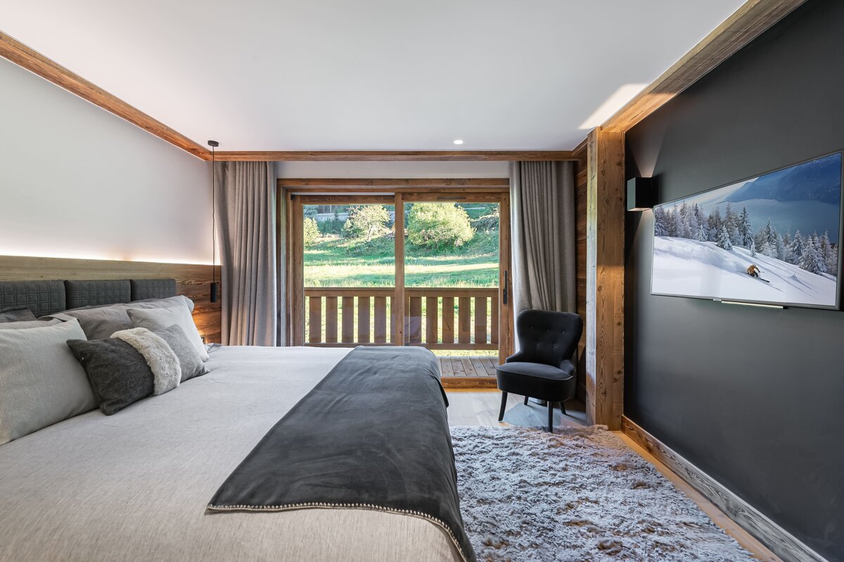 A bedroom with a large bed and a flat screen tv on the wall