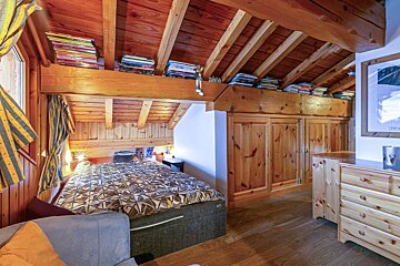 A bedroom with a bed and a dresser with a picture of a skier on the wall