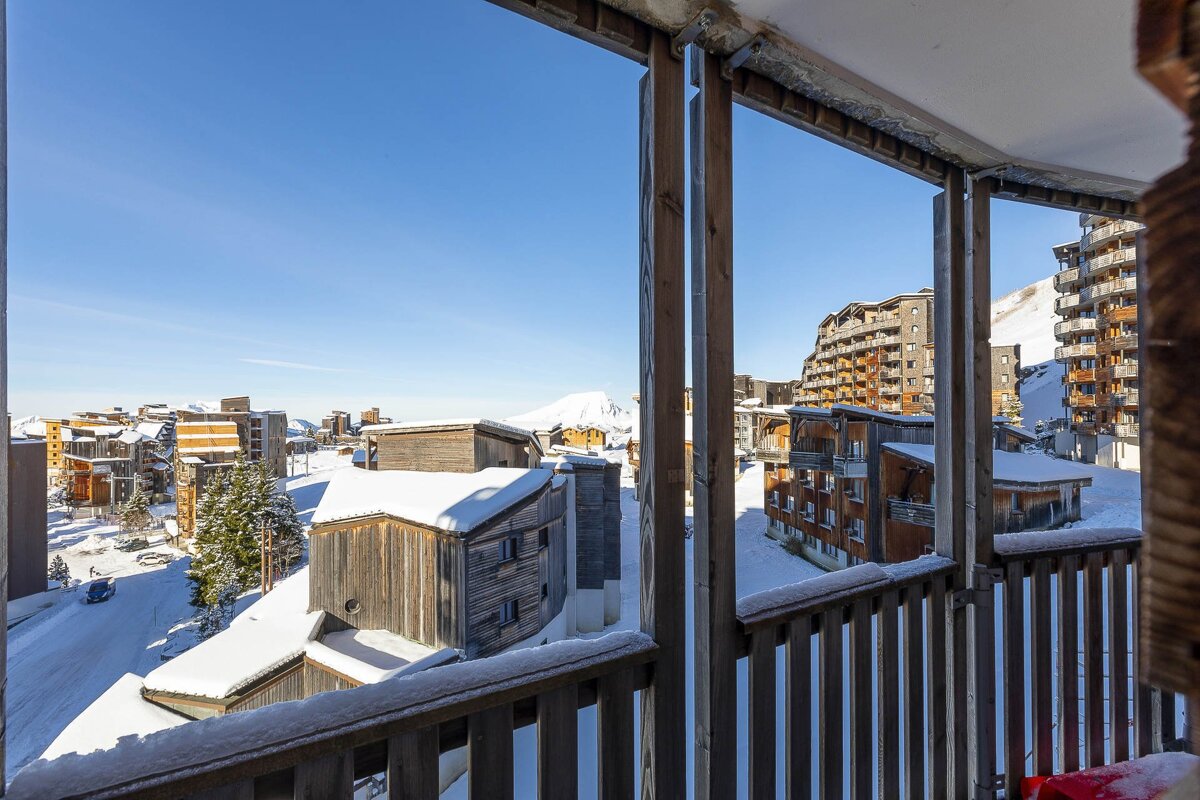 A balcony with a view of snow covered buildings and mountains