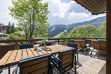 A deck with a table and chairs and a view of the mountains