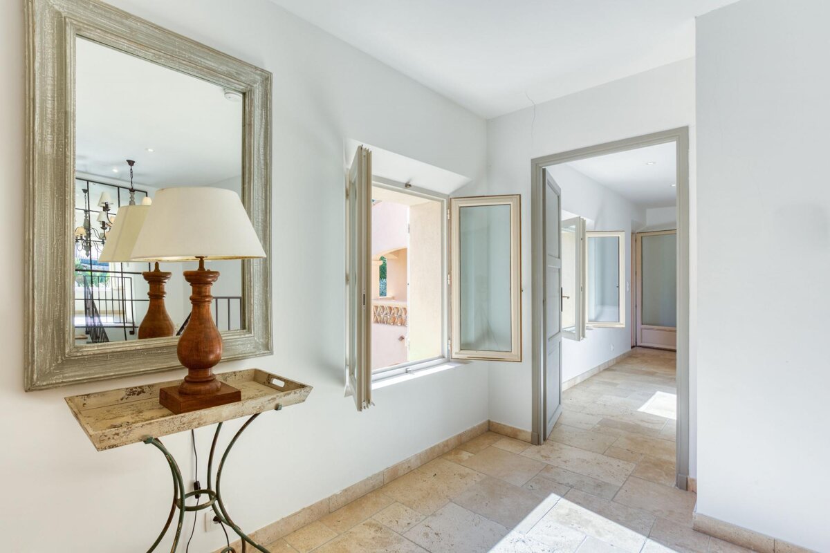 A hallway with a lamp and a mirror on the wall