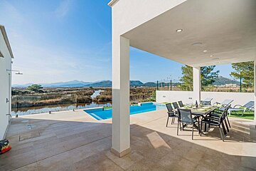 A patio with a table and chairs overlooking a pool
