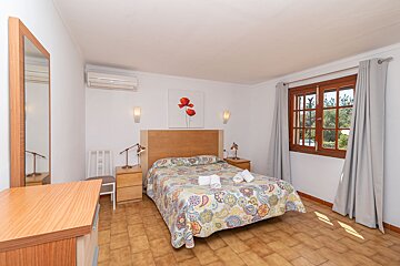 A bedroom with a painting of a flower above the bed