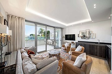 A living room with a couch two chairs and a flat screen tv