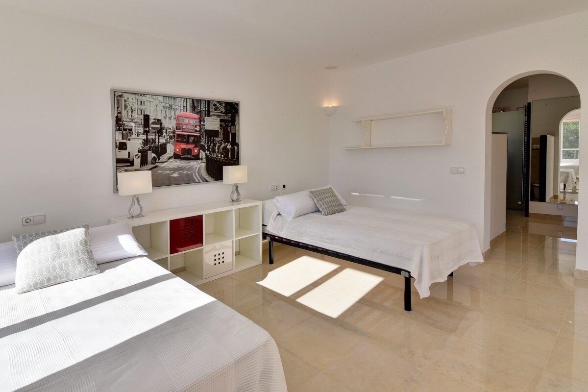 A bedroom with two beds and a picture of a red double decker bus on the wall