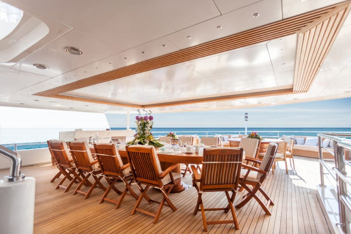 A large table and chairs on a deck overlooking the ocean