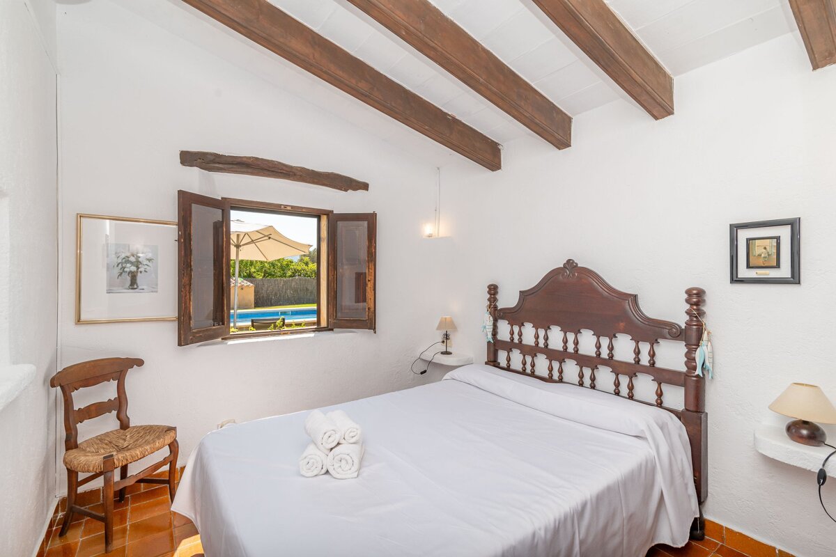 A bedroom with a bed and a window that looks out to a pool