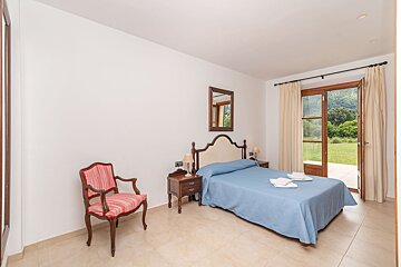 A bedroom with a large bed and a chair