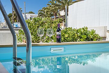 A bottle of wine sits on the edge of a swimming pool