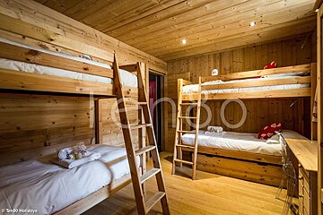 A bunk bed with a ladder in a wooden room
