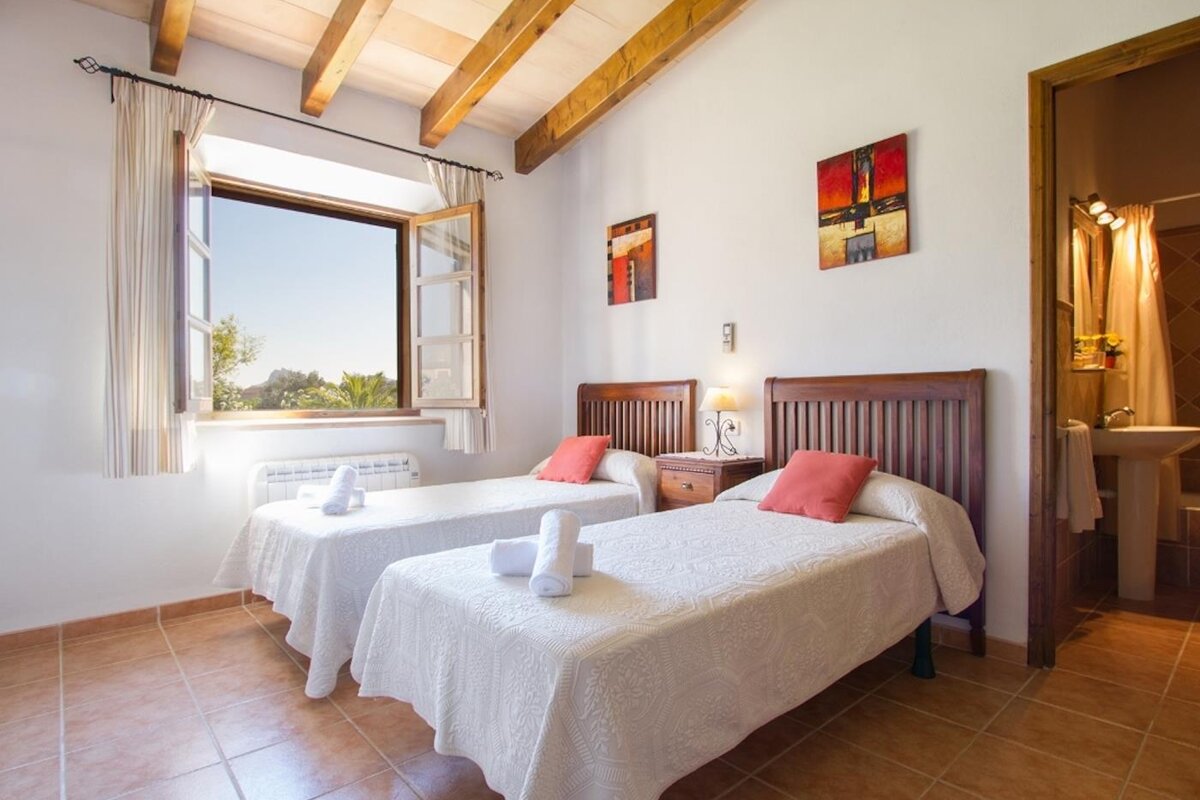 A bedroom with two beds and two paintings on the wall