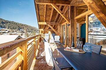 A balcony with a table and chairs and a bottle of champagne