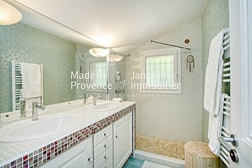 A bathroom with two sinks and a walk in shower made in provence by immobilier