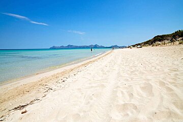 A beach with a blue sky and mountains in the background