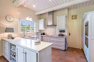 A kitchen with white cabinets and a clock on the wall
