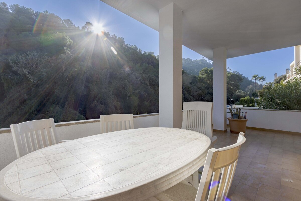 A table and chairs on a balcony with the sun shining through the window