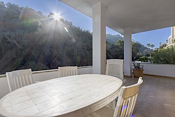 A table and chairs on a balcony with the sun shining through the window