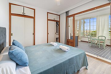 A bedroom with a large bed and a balcony