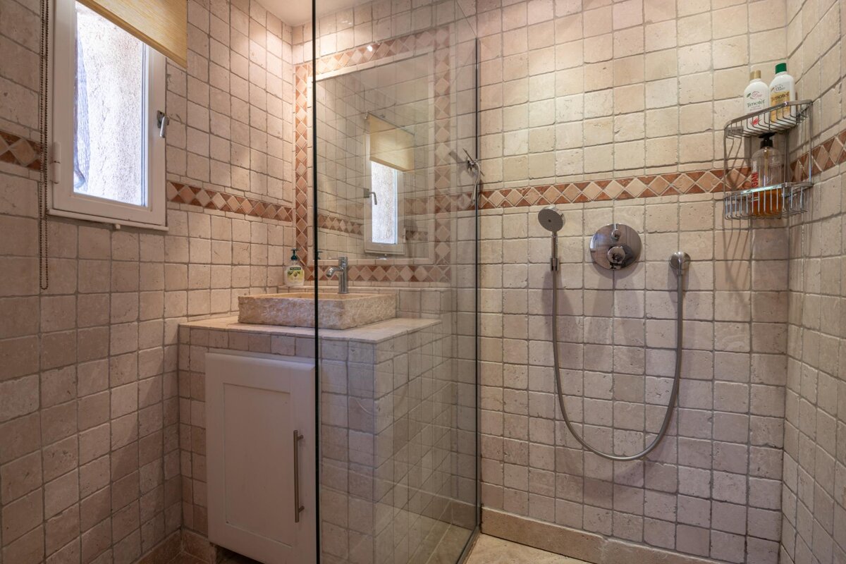 A bathroom with a walk in shower and a sink