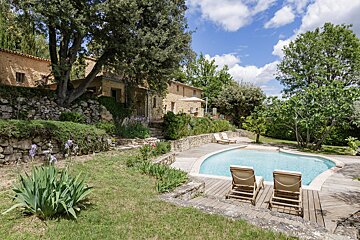 A large swimming pool is surrounded by chairs and a stone wall