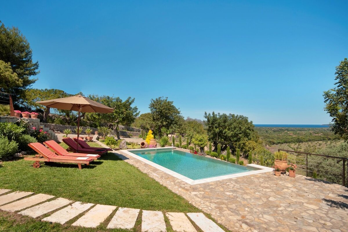 A large swimming pool surrounded by lawn chairs and umbrellas
