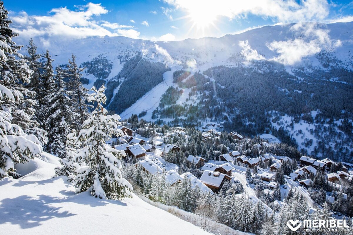 A snowy landscape with a meribel logo in the foreground