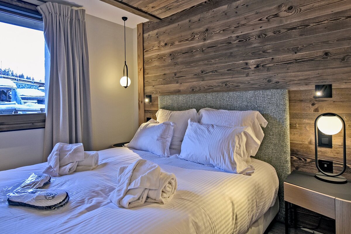 A bed with white sheets and pillows in a hotel room