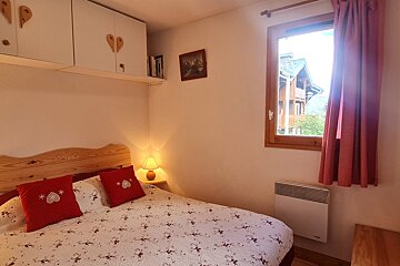 A bedroom with a bed and a window with a picture on the wall