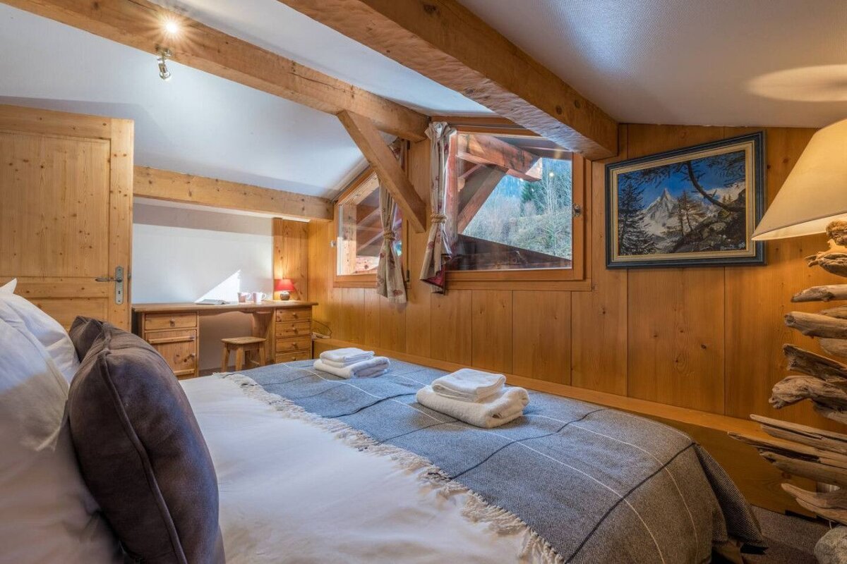 A bedroom with a painting on the wall above the bed
