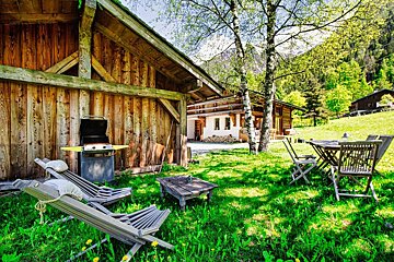 A wooden house with a grill and chairs in front of it