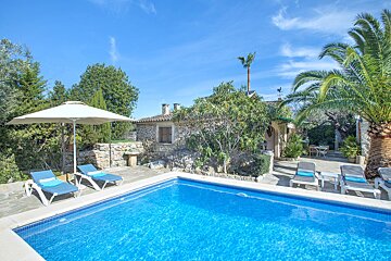 A swimming pool with chairs and an umbrella in front of a house
