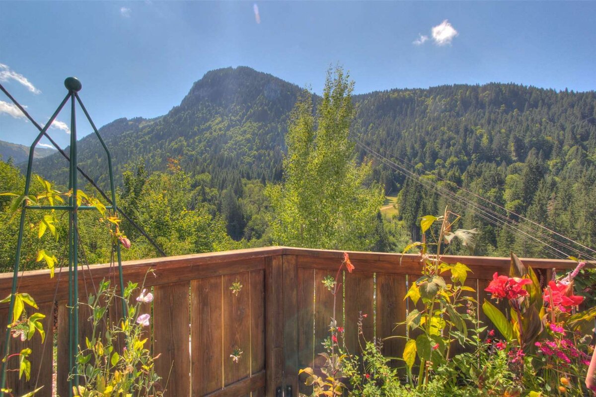 A wooden fence with flowers and a mountain in the background