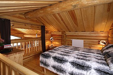 A bedroom in a log cabin with a fur blanket on the bed