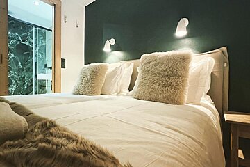 A bed with white sheets and pillows in a bedroom