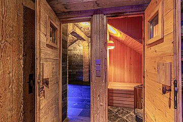 Two open wooden doors reveal a blue-lit steam room on the left and a warm wooden sauna on the right.