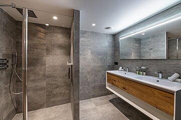A bathroom with two sinks and a walk in shower
