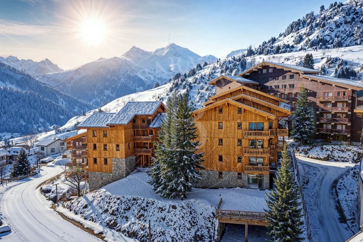 Sun-drenched alpine resort featuring wooden chalets on a snowy mountain slope under a bright blue sky.