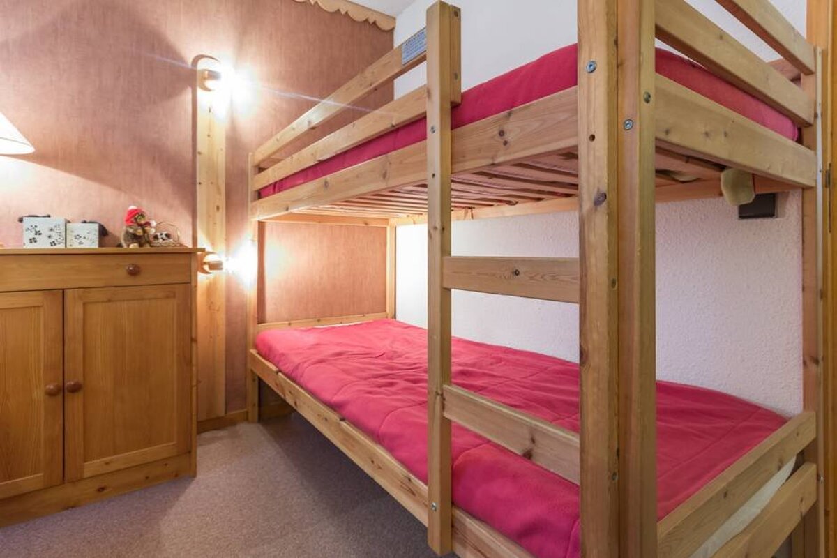 A wooden bunk bed with pink sheets in a bedroom